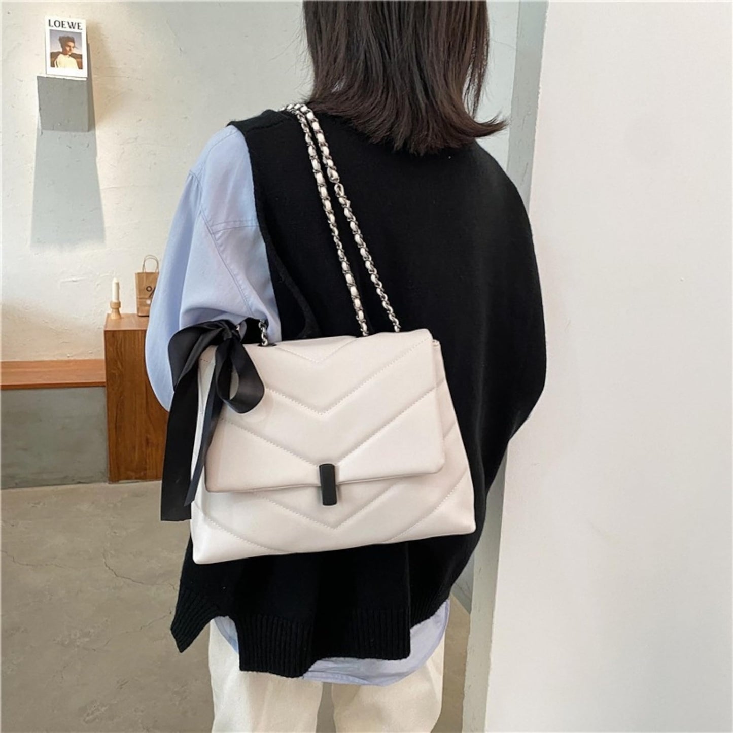fehér steppelt női crossbody táska modellen hátulról hordva láncpánttal